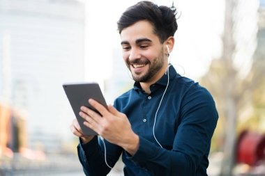 Genç adam dışarıda dijital tabletle video görüşmesi yapıyor..