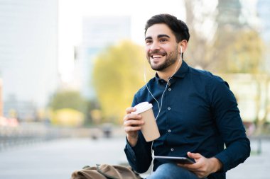 Genç adam dışarıda dijital tablet kullanıyor..