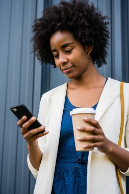 İş kadını cep telefonunu açık havada kullanıyor..