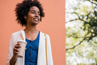 Afro iş kadını elinde bir fincan kahve tutuyor..