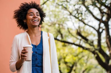 Afro iş kadını elinde bir fincan kahve tutuyor..