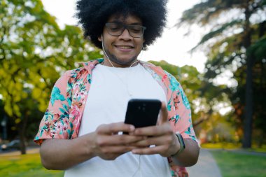 Genç adam cep telefonunu açık havada kullanıyor..