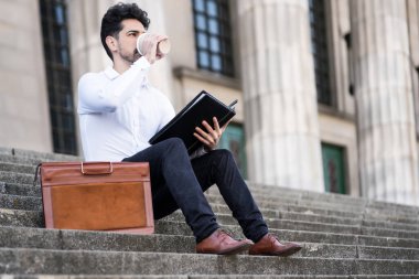 İşadamı merdivenlerde otururken dosyaları okuyor..