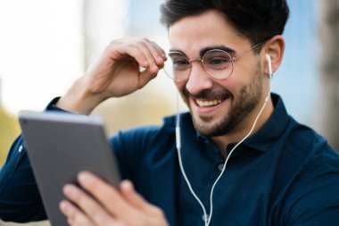 Genç adam dışarıda dijital tabletle video görüşmesi yapıyor..