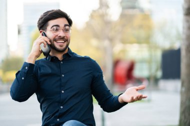 Genç adam dışarıda telefonla konuşuyor..