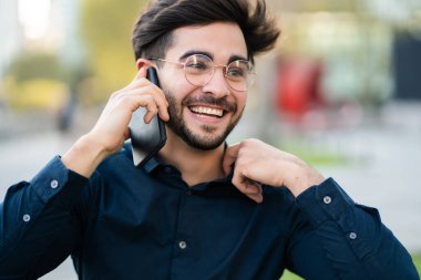 Genç adam dışarıda telefonla konuşuyor..