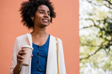 Afro iş kadını elinde bir fincan kahve tutuyor..