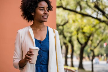 Afro iş kadını elinde bir fincan kahve tutuyor..