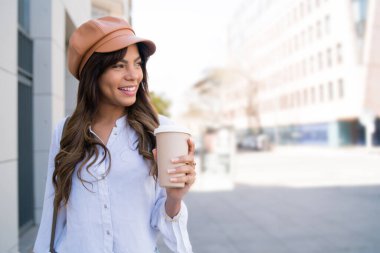 Elinde kahve tutan genç bir kadın..