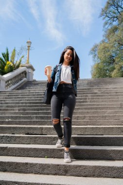 Elinde kahve tutan genç bir kadın..