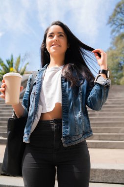 Elinde kahve tutan genç bir kadın..