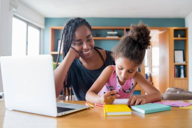 Ev okulunda kızına yardım eden bir anne..