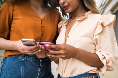 Dışarıda cep telefonu kullanan iki arkadaş..