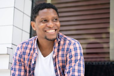 Afro-Amerikalı bir adam mağazanın vitrininde oturuyor..