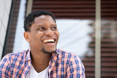 Afro-Amerikalı bir adam mağazanın vitrininde oturuyor..