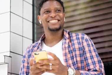 Sokakta telefonunu kullanan Afrikalı Amerikalı bir adam..