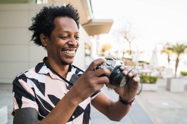 Afro turist dışarıda kamerayla fotoğraf çekiyor..