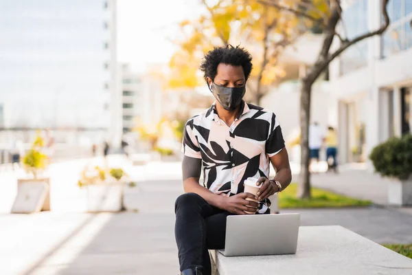 Afro man använder sin bärbara dator utomhus. — Stockfoto