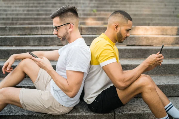 Γκέι ζευγάρι αγνοούν ο ένας τον άλλο ενώ χρησιμοποιούν τα τηλέφωνά τους. — Φωτογραφία Αρχείου