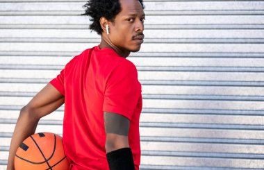 Dışarıda basketbol topu tutan Afro bir sporcu..