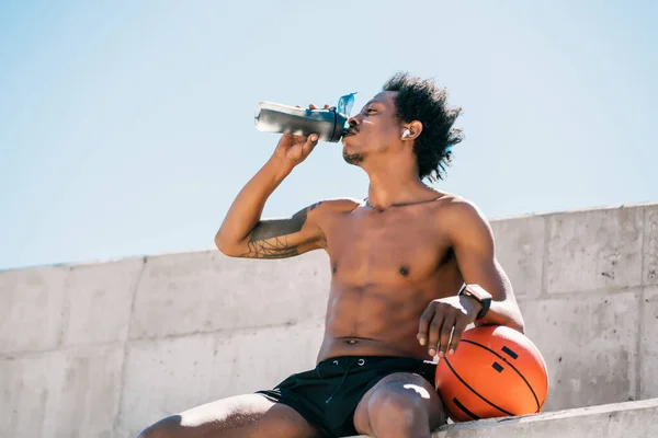 Atletisk man dricksvatten efter träning utomhus. — Stockfoto