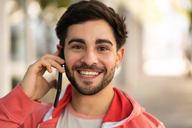 Genç adam dışarıda telefonla konuşuyor..