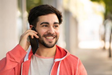 Genç adam dışarıda telefonla konuşuyor..