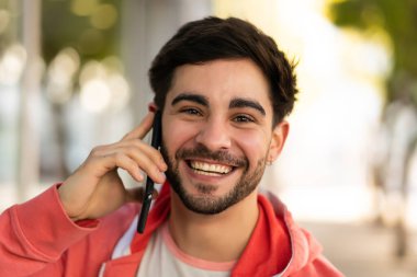 Genç adam dışarıda telefonla konuşuyor..