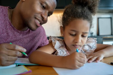 Bir baba kızına ev okulunda yardım ediyor..