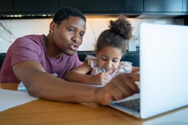 Bir baba kızına ev okulunda yardım ediyor..