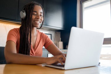 Evde dizüstü bilgisayarlı bir kadın var..