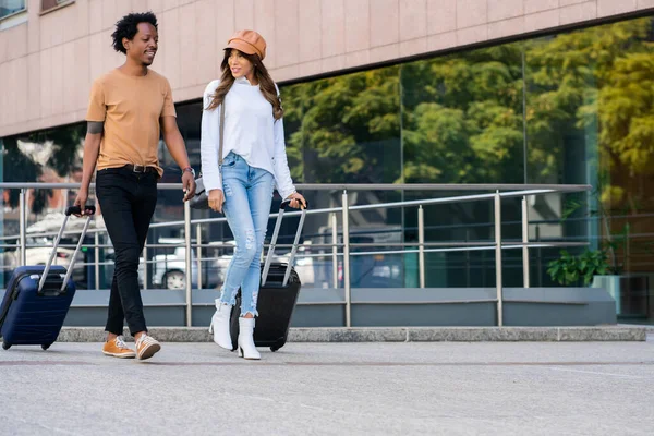 Casal de turistas carregando mala enquanto caminhava ao ar livre. — Fotografia de Stock