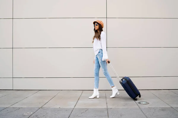 Ung kvinna som bär en resväska utomhus. — Stockfoto