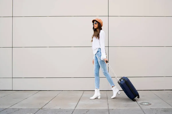 Young woman carrying a suitcase outdoors. — Stock Photo, Image