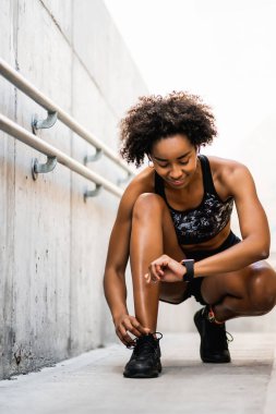 Afro atlet kadın ayakkabı bağcıklarını bağlıyor.