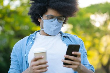 Genç adam cep telefonunu açık havada kullanıyor..