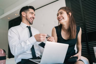 Çevrimiçi ödeme için kredi kartı kullanan iki işadamı.