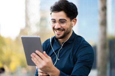 Genç adam dışarıda dijital tabletle video görüşmesi yapıyor..
