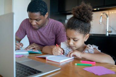 Bir baba kızına ev okulunda yardım ediyor..