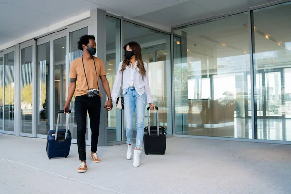 Casal de turistas carregando mala enquanto caminhava ao ar livre. — Fotografia de Stock