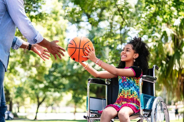 Kleines Mädchen im Rollstuhl spielt Basketball mit ihrem Vater. — Stockfoto