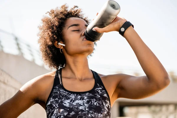 Afro αθλητής γυναίκα πόσιμο νερό μετά την άσκηση έξω στο ύπαιθρο. — Φωτογραφία Αρχείου