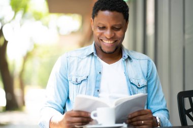Kahve dükkanında kitap okuyan adam..