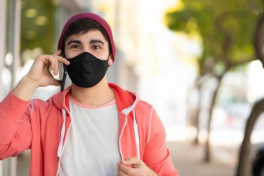 Genç adam dışarıda telefonla konuşuyor..