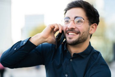 Genç adam dışarıda telefonla konuşuyor..