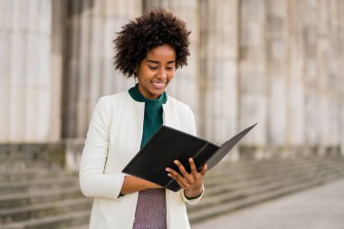 Afro iş kadını elinde bir pano ile sokakta bekliyor..