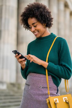 İş kadını cep telefonunu açık havada kullanıyor..