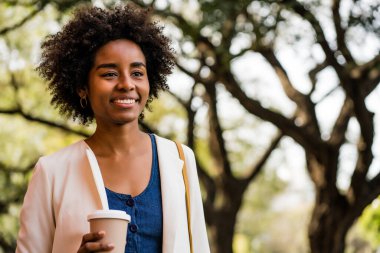 Afro iş kadını elinde bir fincan kahve tutuyor..
