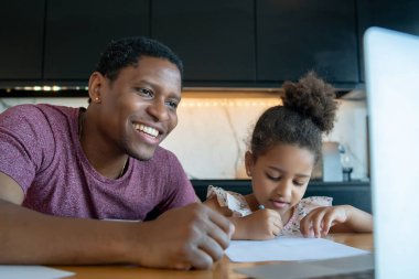 Bir baba kızına ev okulunda yardım ediyor..