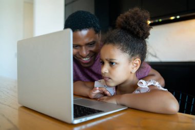 Bir baba kızına ev okulunda yardım ediyor..